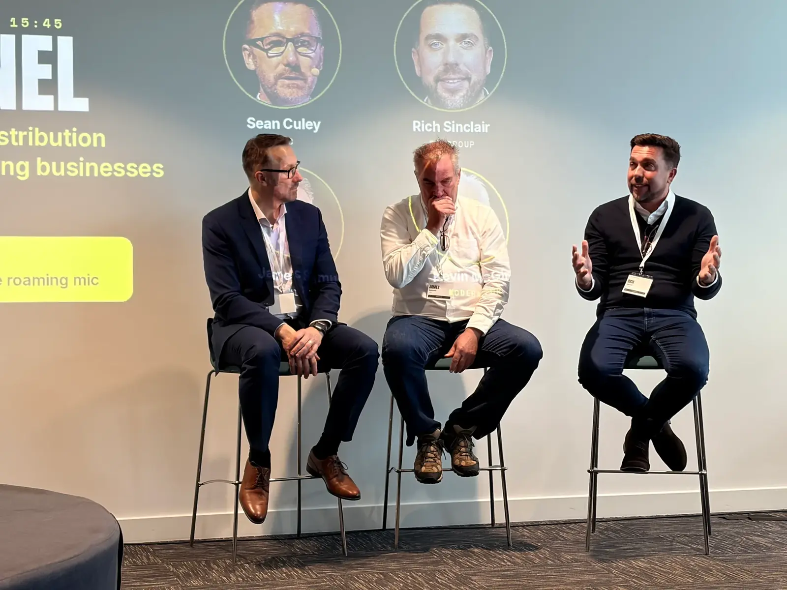 The AI panel on stools in front of the branded panel slide